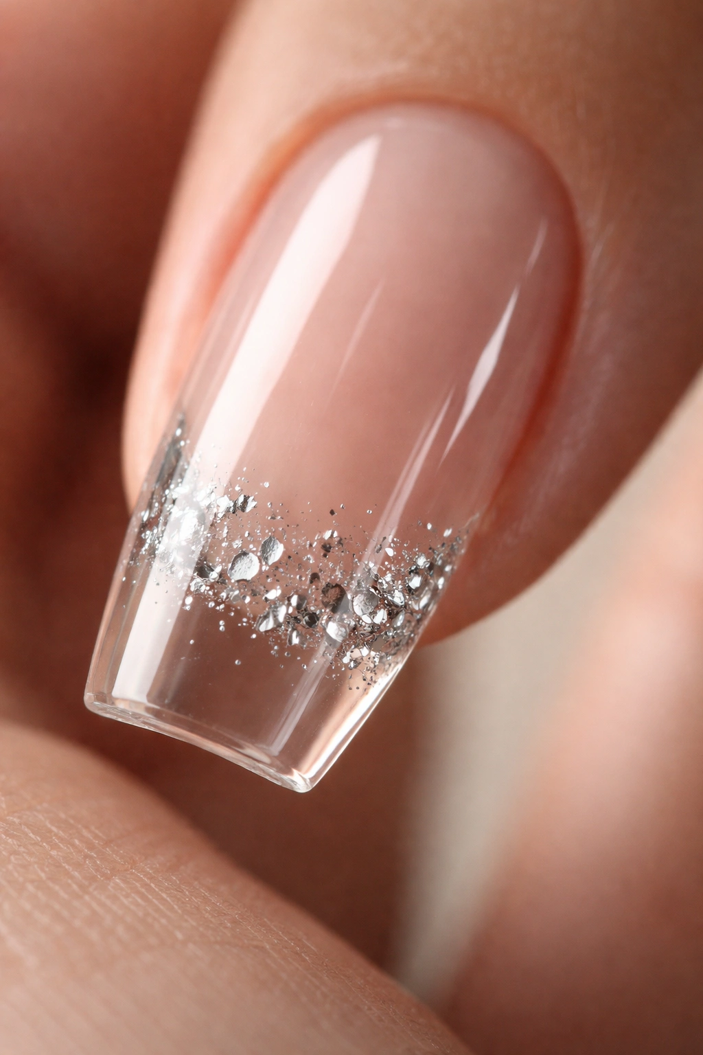 Close-up of a transparent coffin nail with tiny silver foil flecks near the tip encapsulated in clear gel