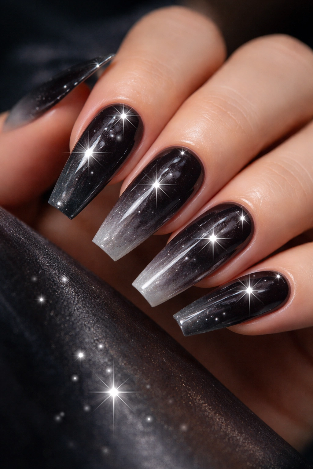 Close-up of coffin nails with smoky black ombre and silver starbursts, glossy finish