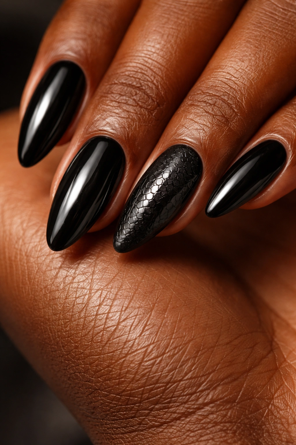 Close-up of black almond nails with subtle snake-skin texture