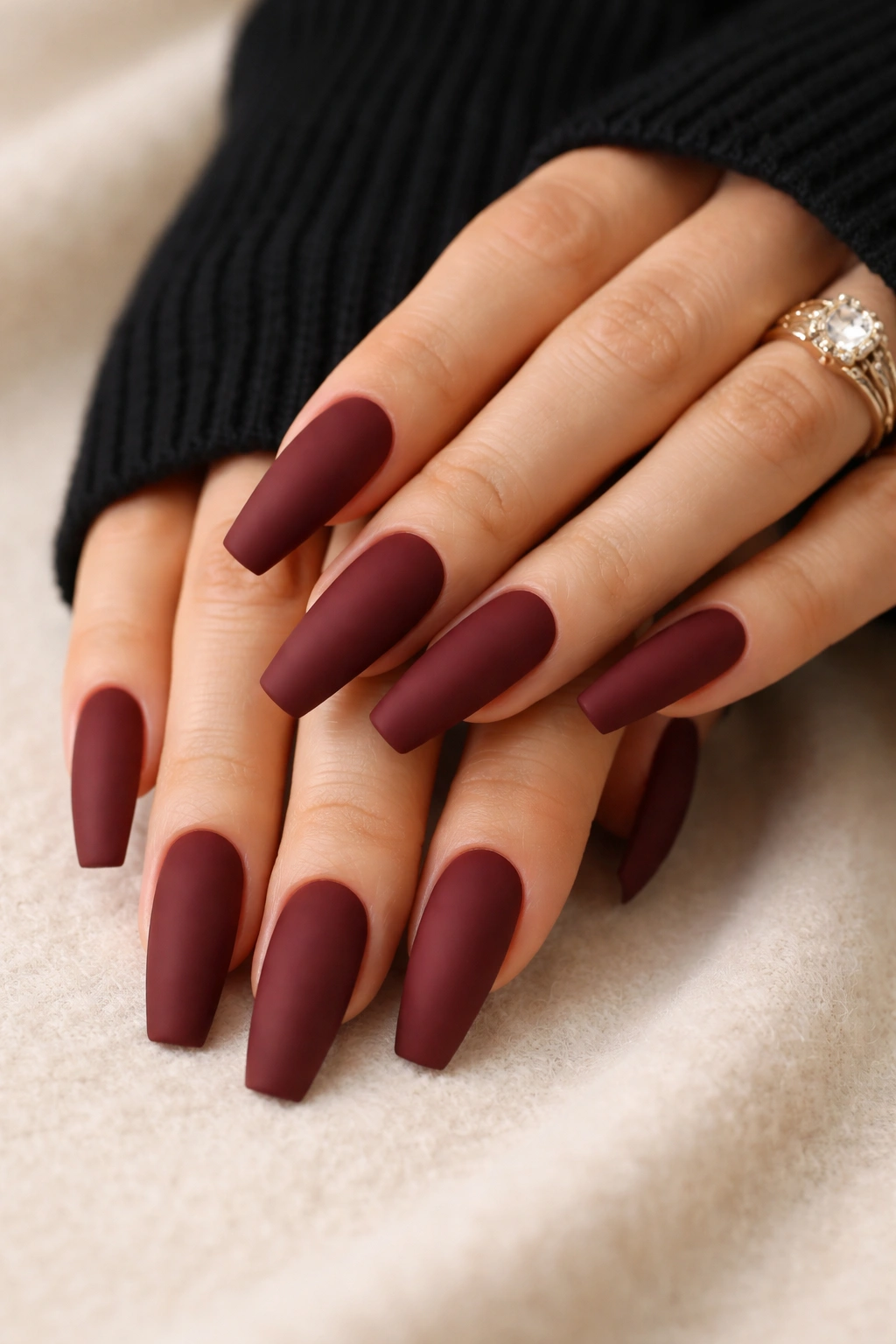 Close-up of solid burgundy matte coffin nails on a tapered hand