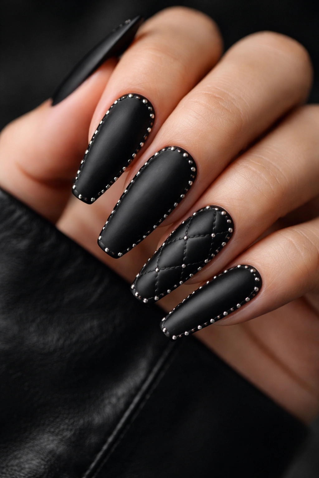 Close-up of matte black coffin nails with tiny silver studs