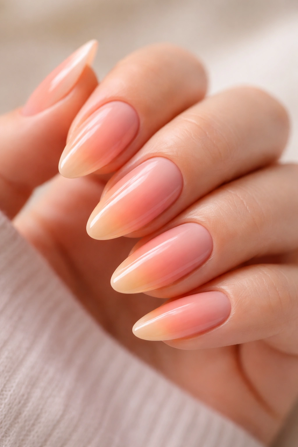 Close-up of almond nails with sunset sorbet ombre in peach, pink, and apricot