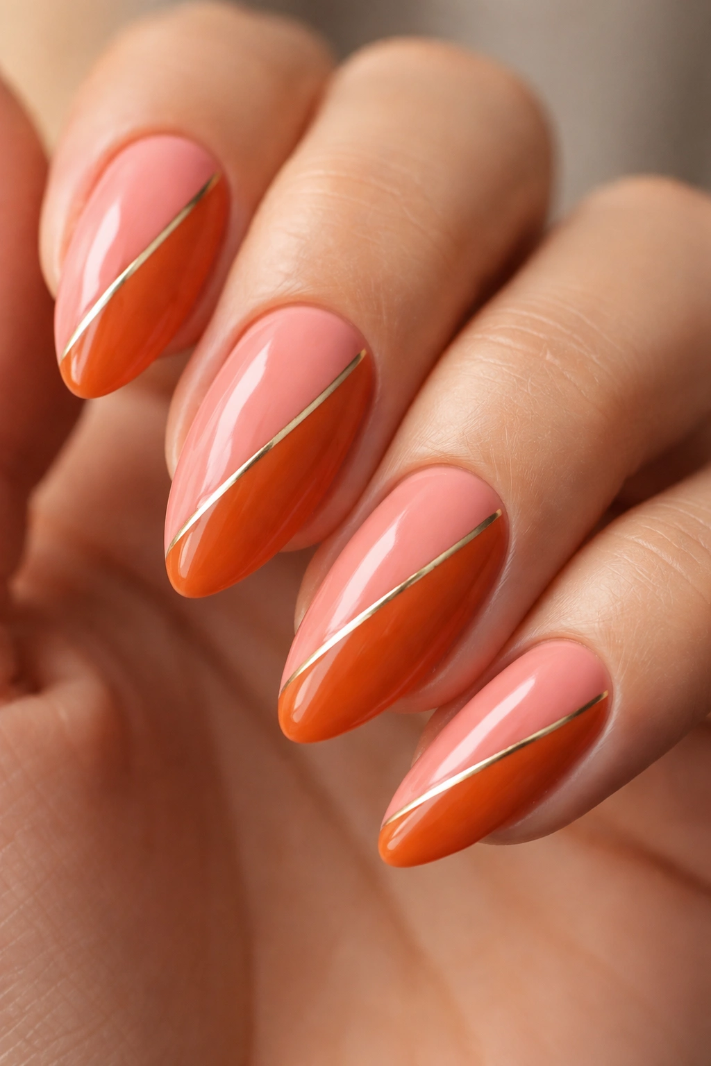 Almond nail with diagonal coral and burnt orange split with gold line