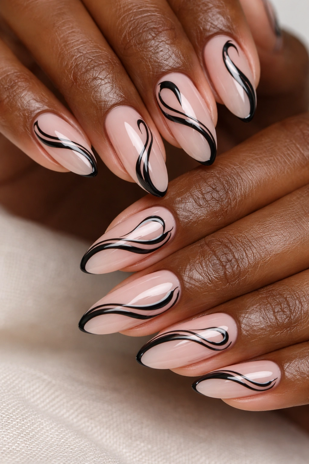 Close-up of sheer pink nails with black swirls on deep skin