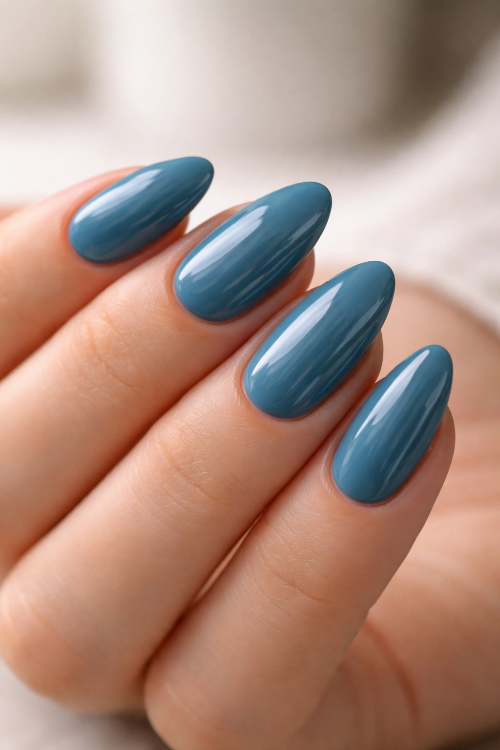 Shorter almond nails painted teal-blue with glossy finish