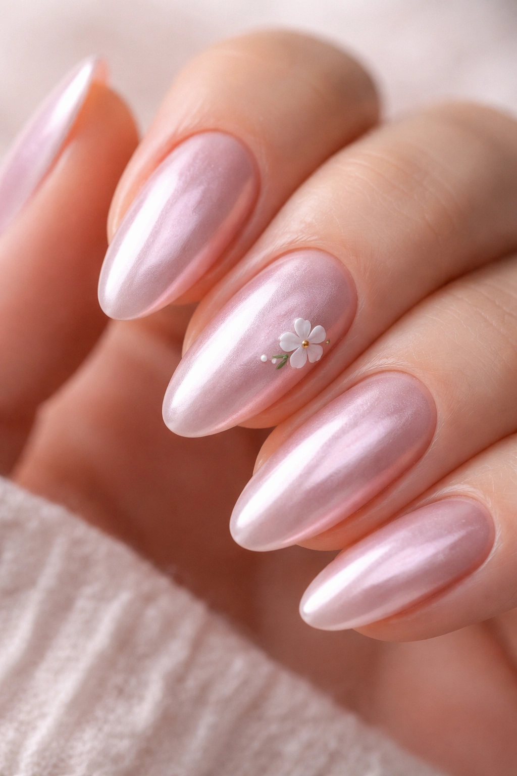 One almond nail with pink chrome and a tiny white floral accent.