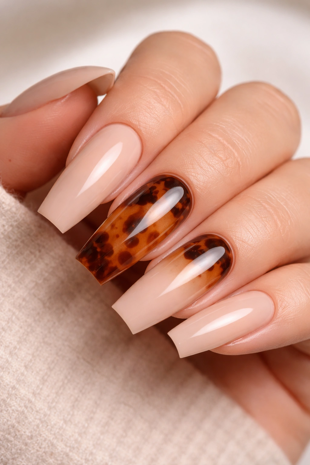 Two tortoiseshell accent coffin nails on a warm nude base