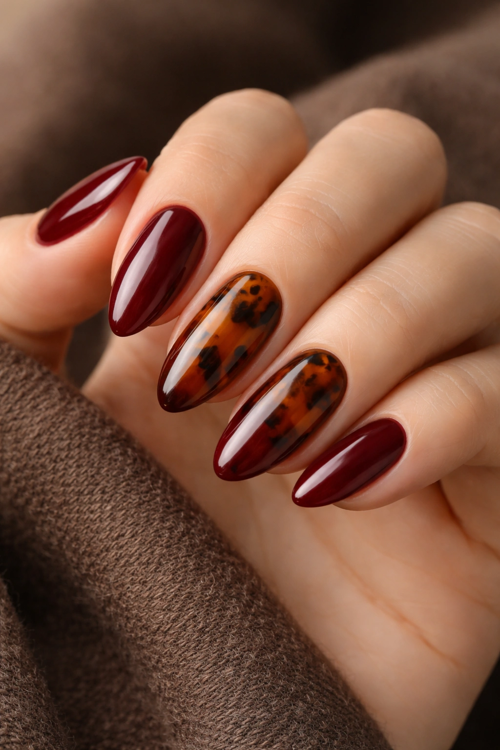 Almond nails with tortoiseshell accents on two nails and maroon on the rest