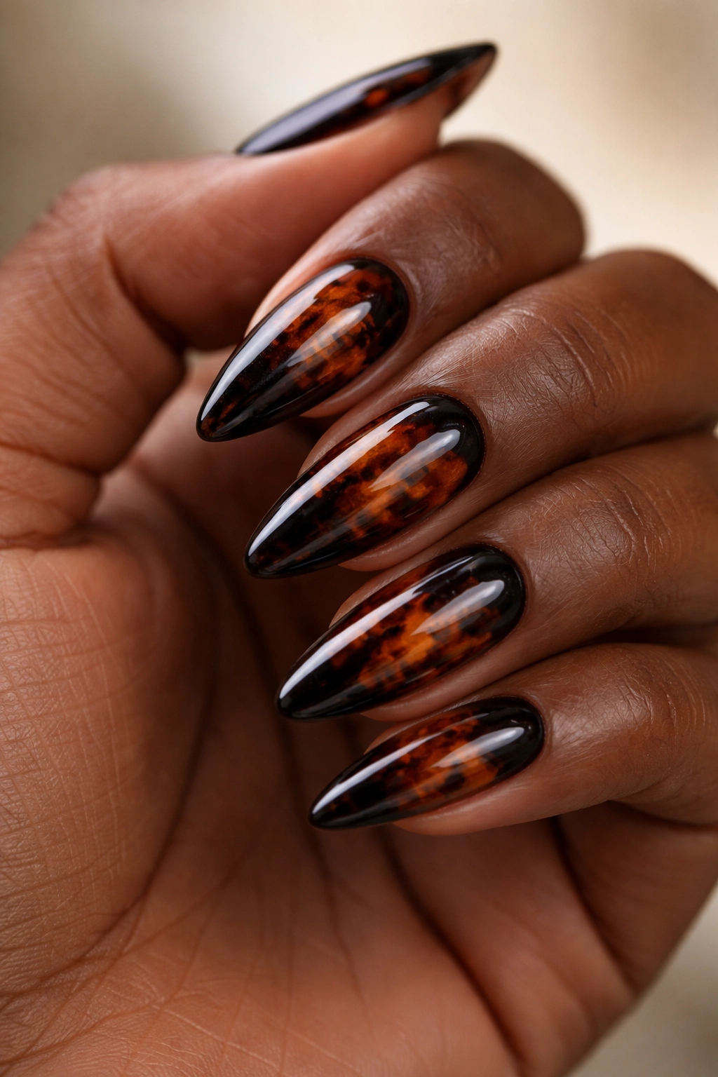 Close-up of almond nails with tortoiseshell pattern on dark skin