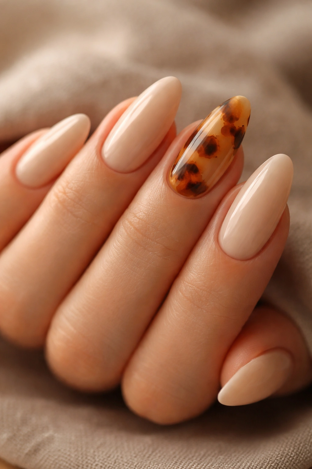 Beige nails with tortoiseshell accent nails on an almond shape