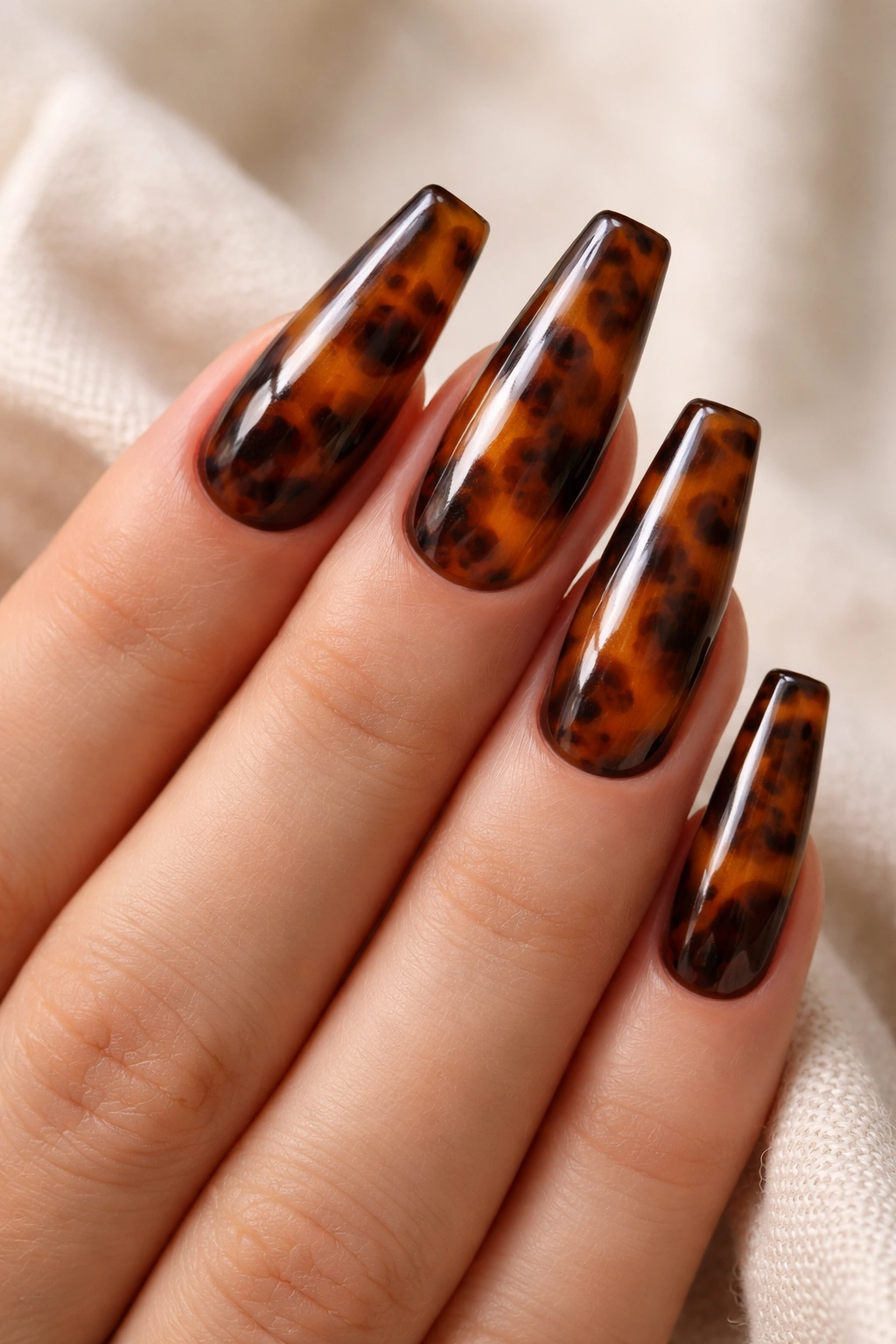 Close-up of brown tortoiseshell coffin nails with warm amber and espresso patches on a neutral background