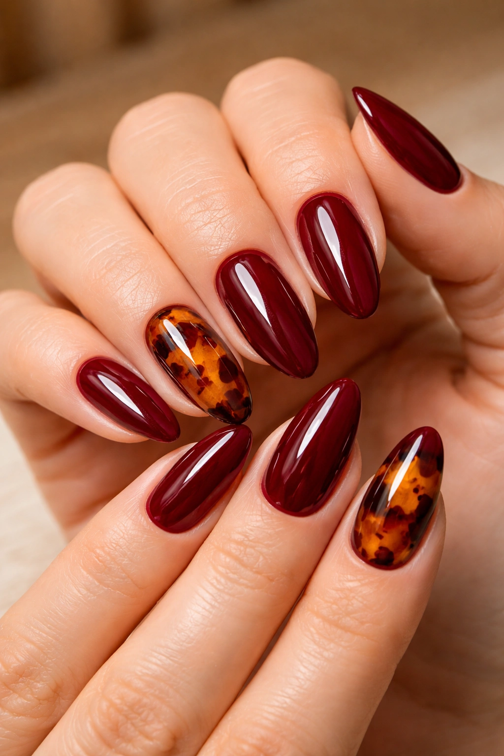 Almond nails with tortoiseshell pattern on accent nails and dark red others.