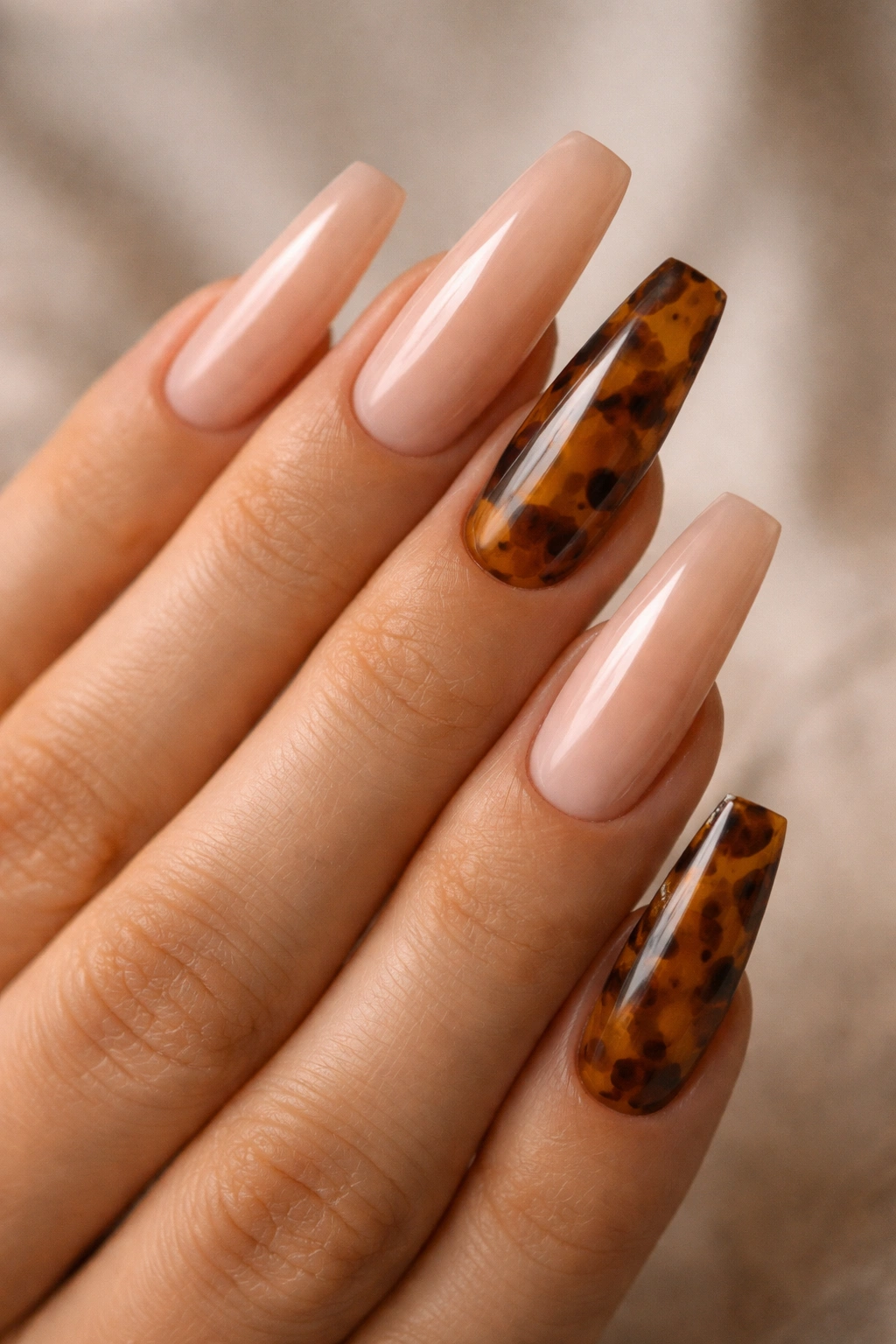 Nude coffin nails with tortoiseshell accents on select nails