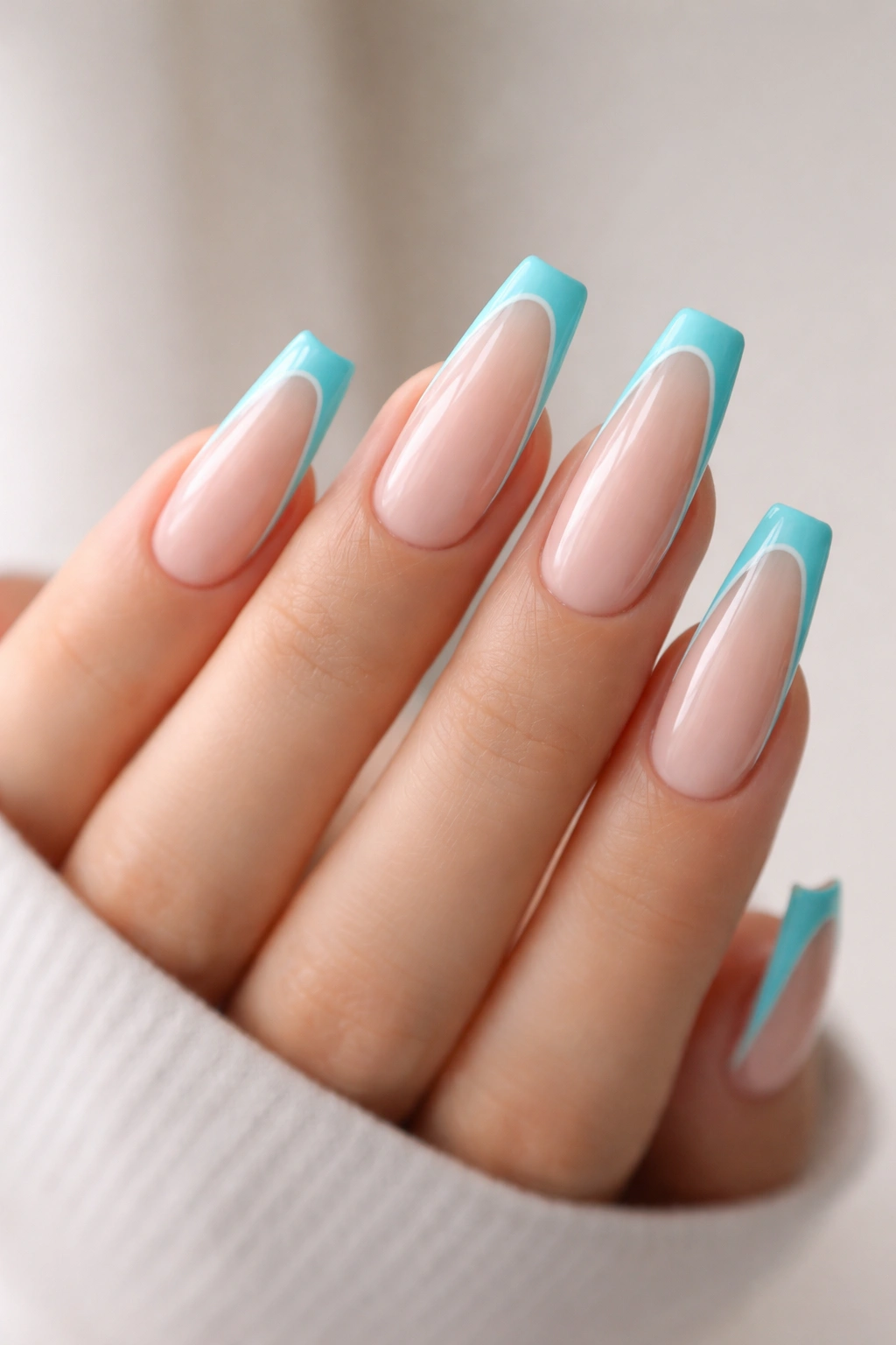 Close-up of coffin nails featuring a turquoise outline French with nude center.