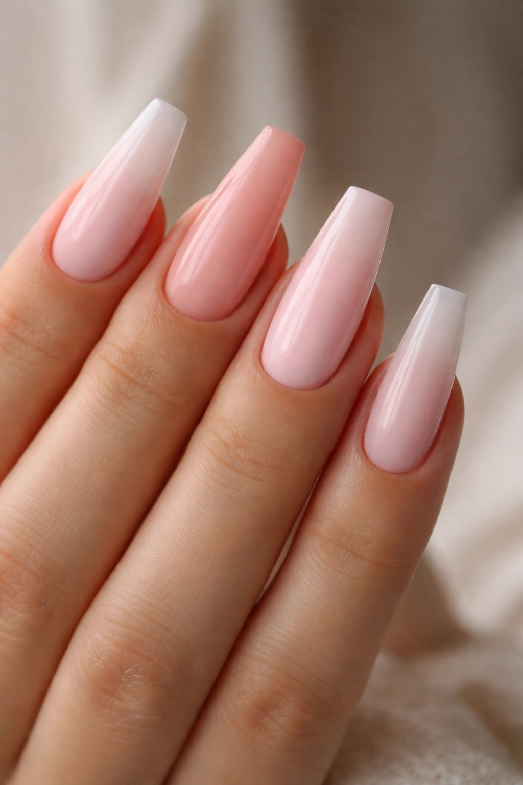 Hand with coffin nails showing undertone and opacity variations on nails.