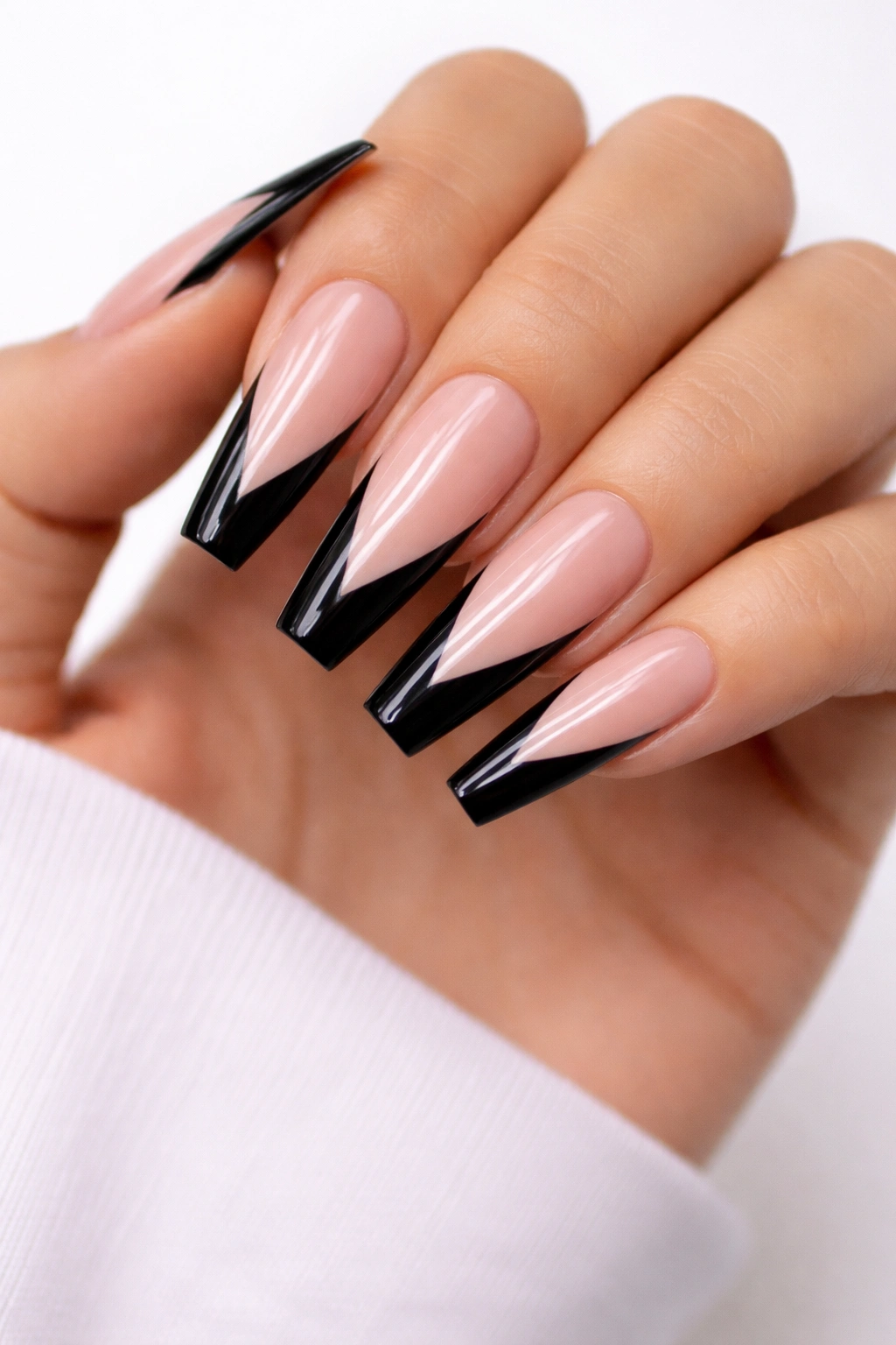 Close-up of long coffin nails with a deep V-shaped black tip on a translucent nude base.