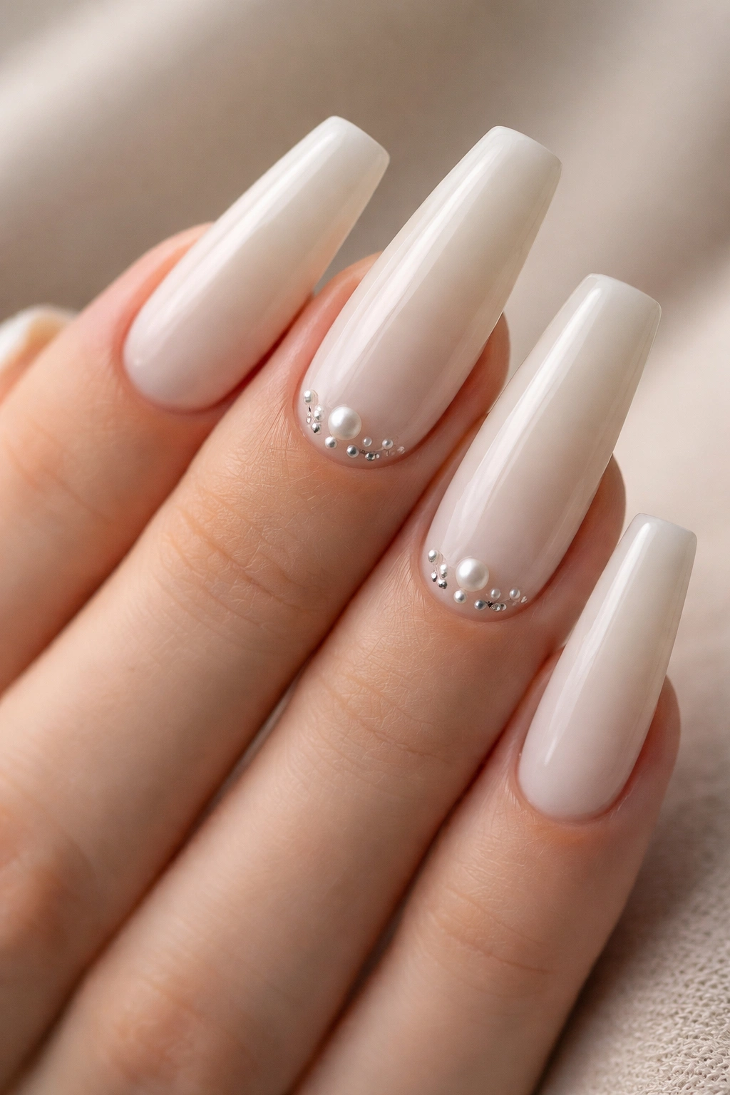 Close-up of coffin nails with vanilla base and small pearls near the cuticle