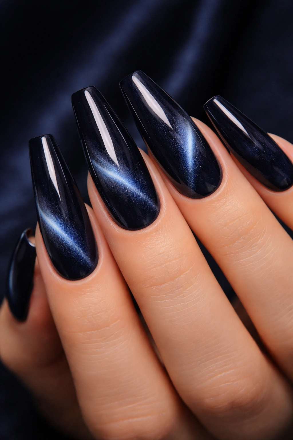 Close-up of velvet navy cat-eye coffin nails with shimmering movement
