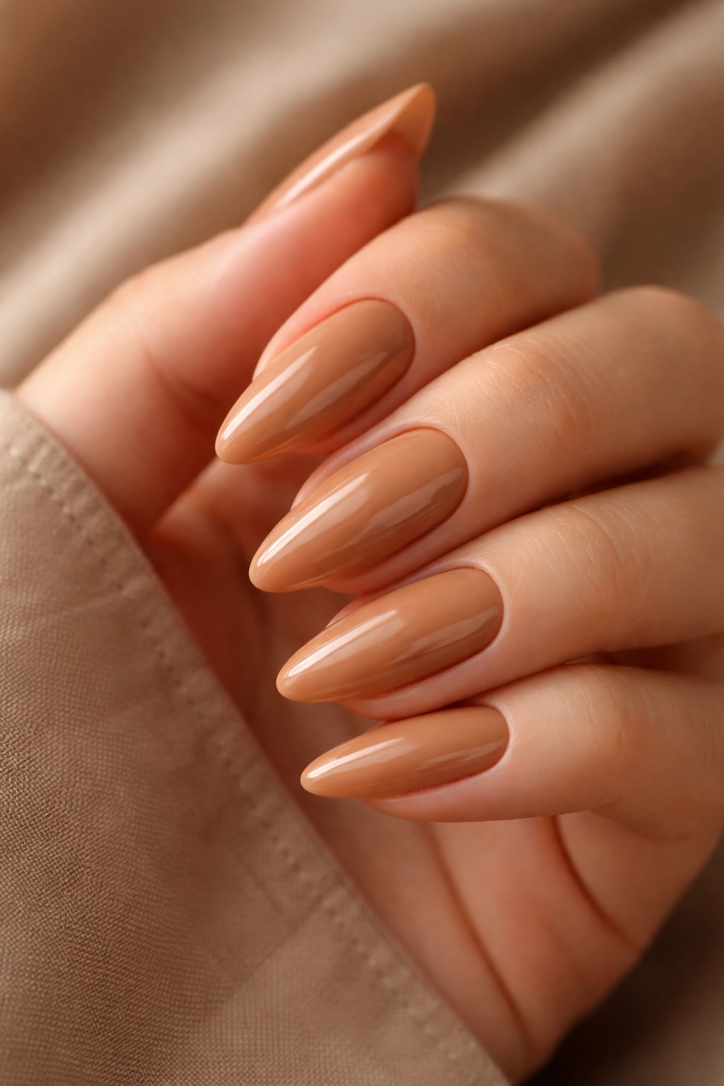 Close-up of almond nails in warm caramel nude with glossy finish