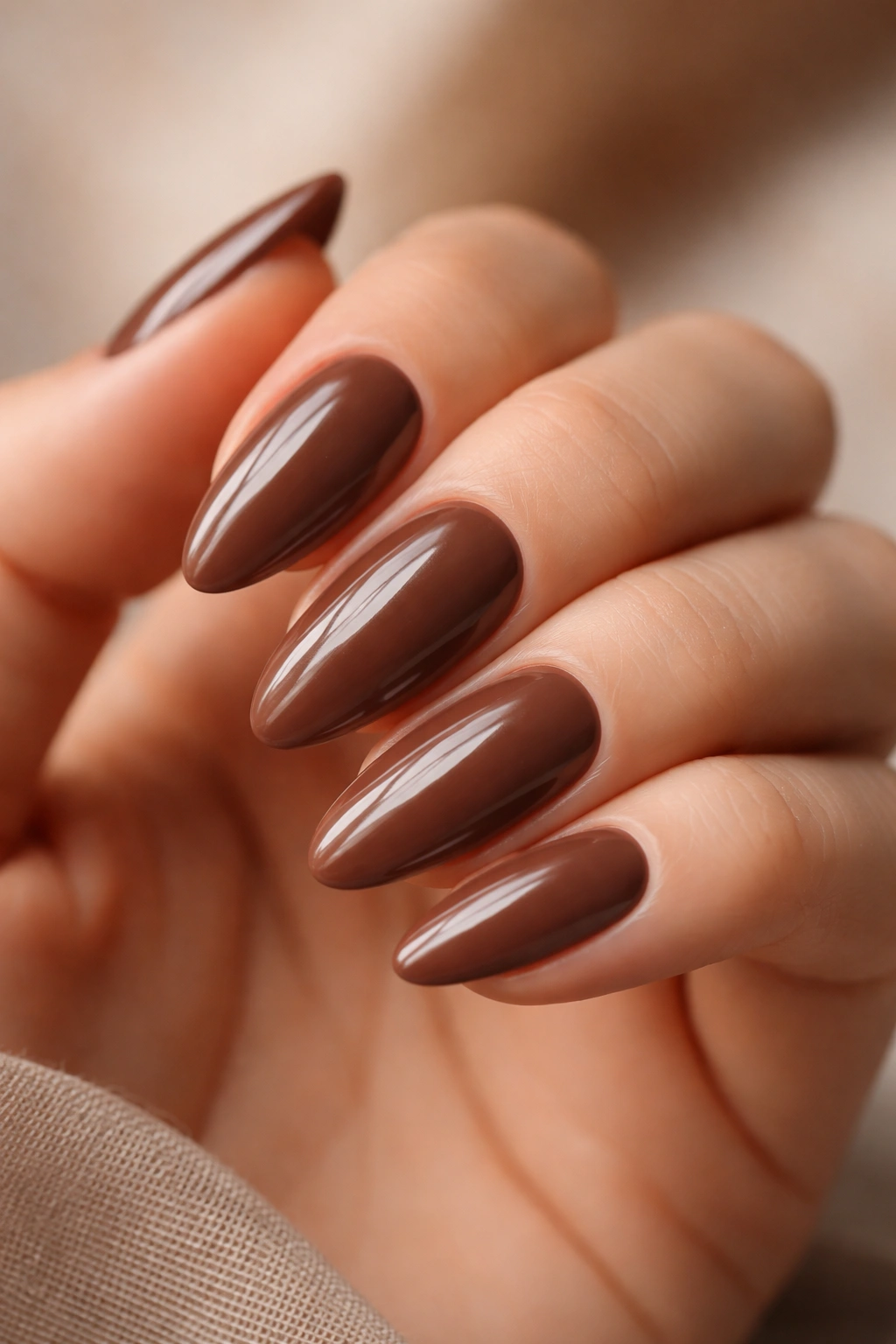 Close-up of almond nails in a warm mocha glossy finish