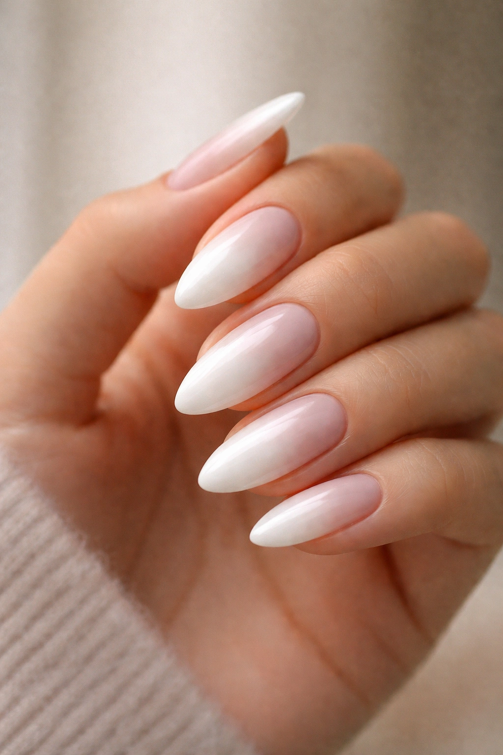 Close-up of almond nails with a soft centered glow on a nude base