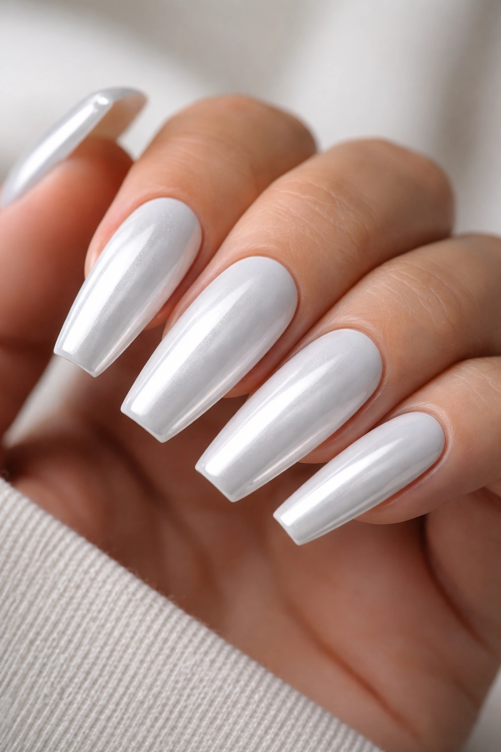 Close-up of coffin nails with a cool white base under chrome showing a clean, glossy finish