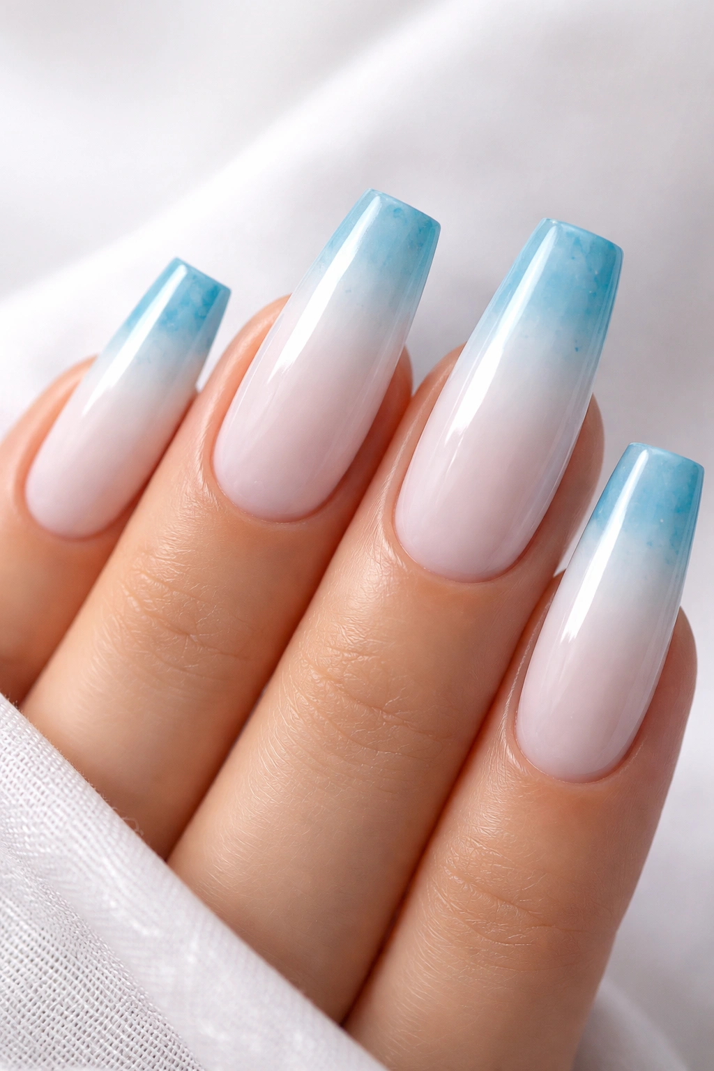 Close-up of coffin nails with translucent white base and ocean-tinted blue tips.