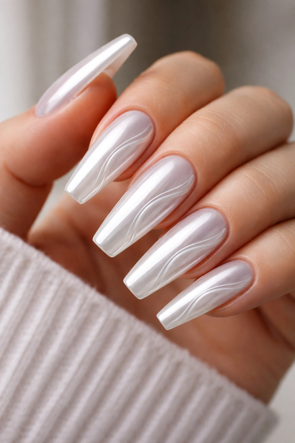 Close-up of white chrome coffin nails with subtle 3D gel swirl ridges catching light