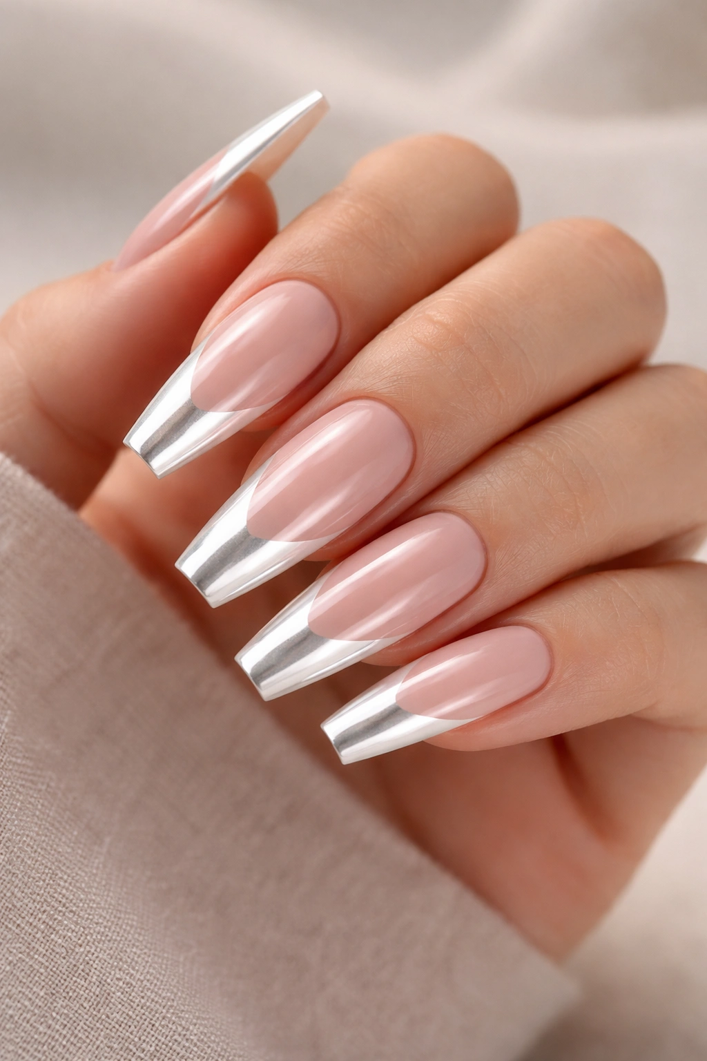 Close-up of nude-based coffin nails with white chrome French tips reflecting light