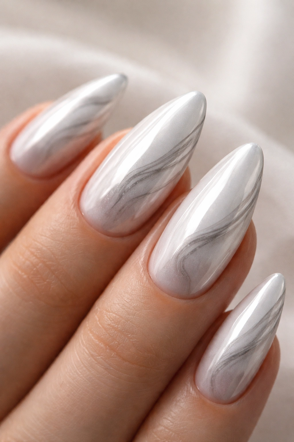 Close-up of almond nail with white chrome and soft gray smoke swirls on a neutral backdrop