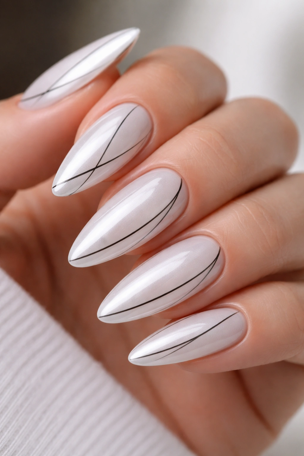 Close-up of White Chrome with Fine Black Line Art on almond nails with a precise black line