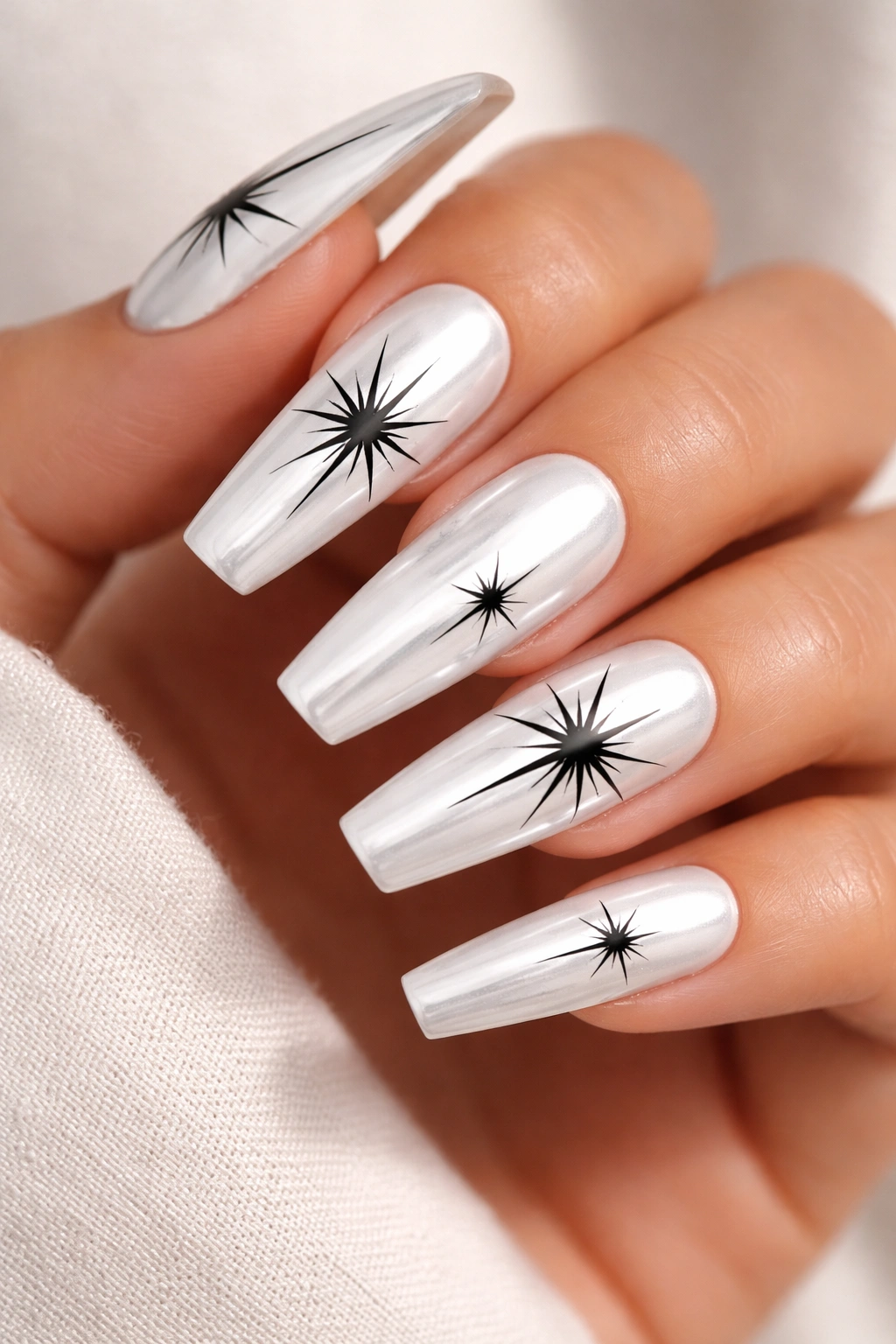 White chrome coffin nails with black starburst shapes.