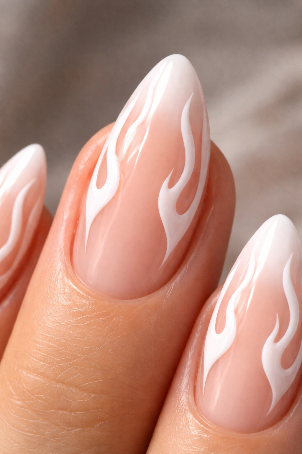 Close-up of an almond nail with white flame tips on a sheer nude base