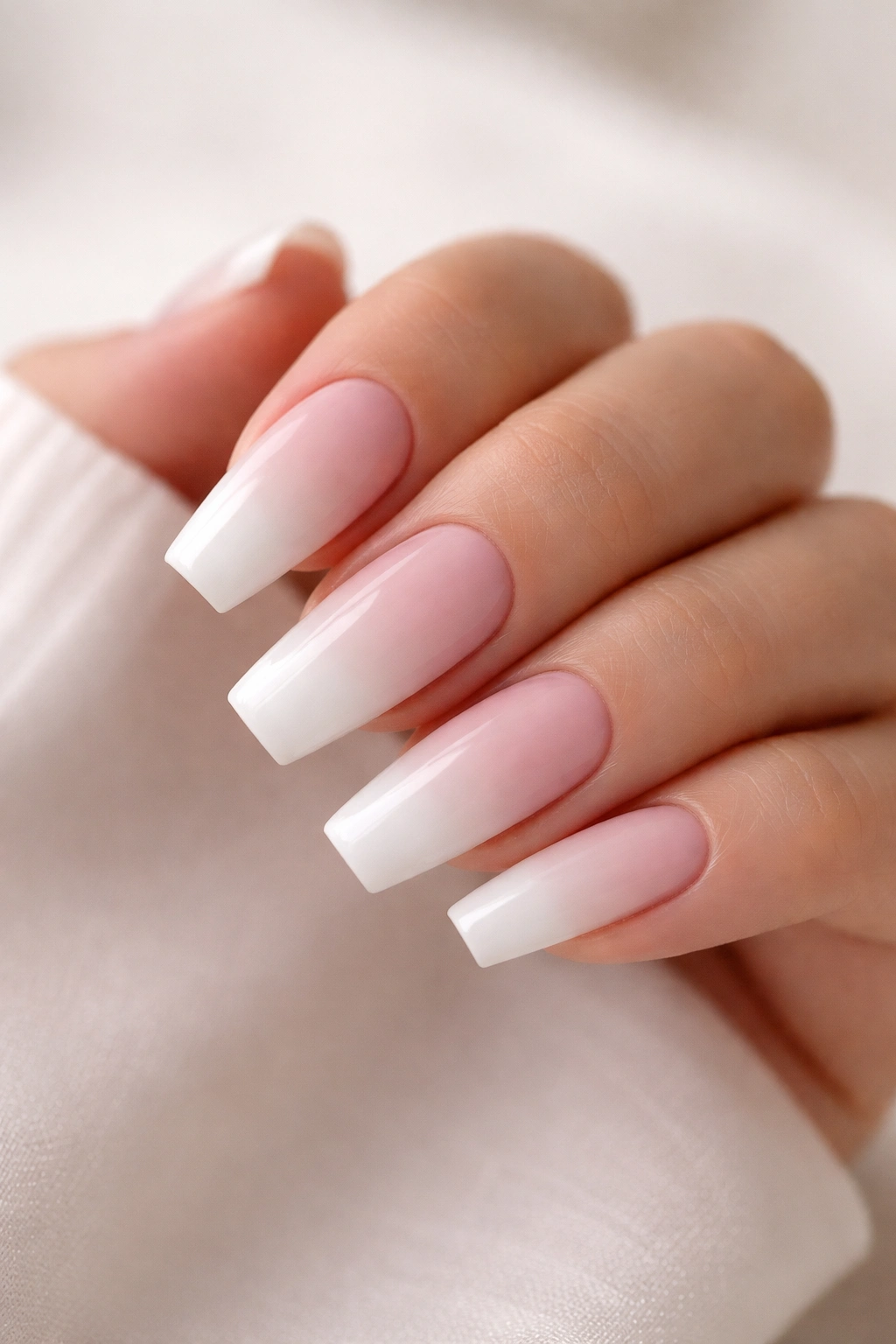 Close-up of white-heavy ombre coffin nails with soft bridal edge on pale pink base