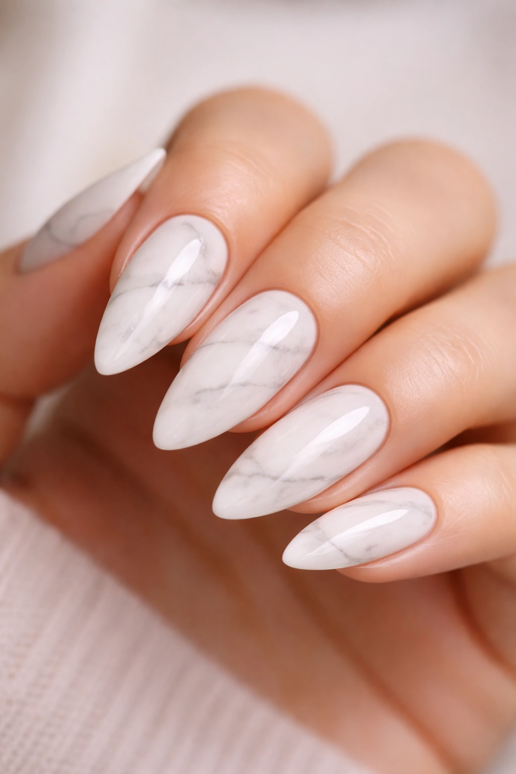 Close-up of white marble almond nails with delicate gray veins