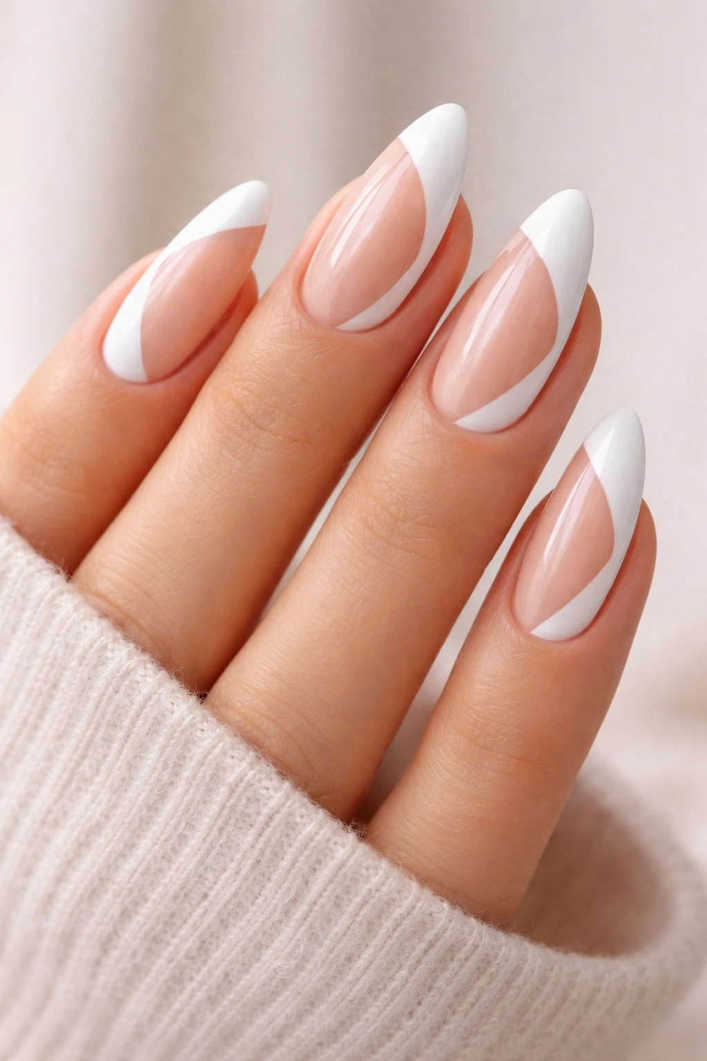 Close-up of almond nails with white negative-space shapes on a nude base