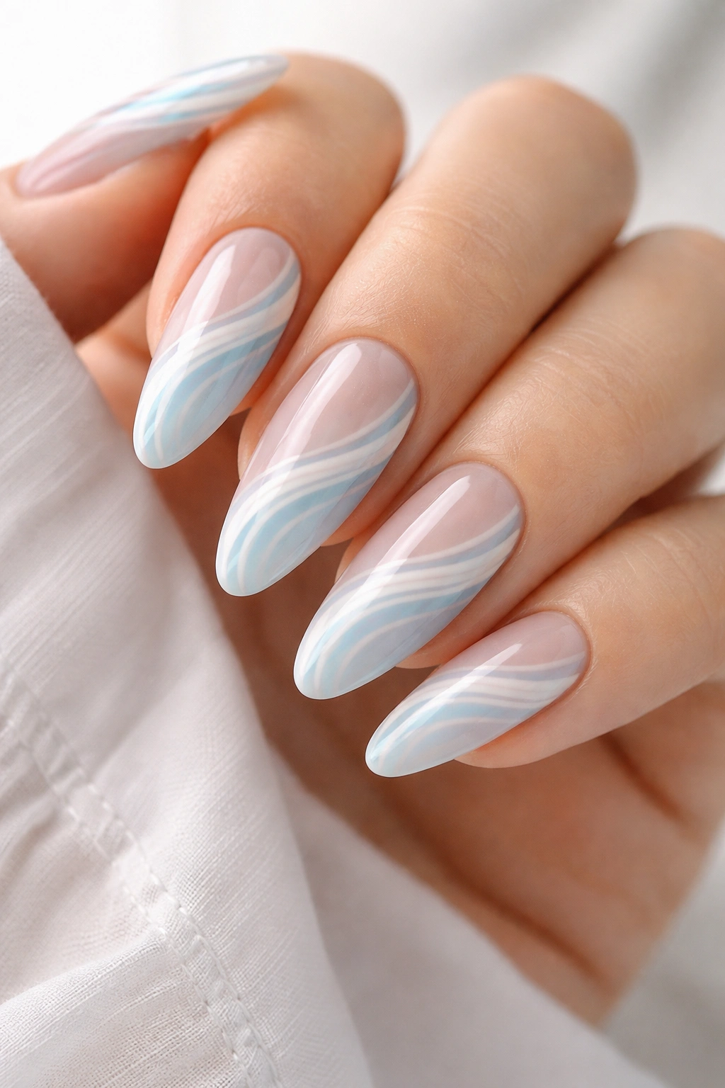Close-up of almond nails with white and pastel blue swirls