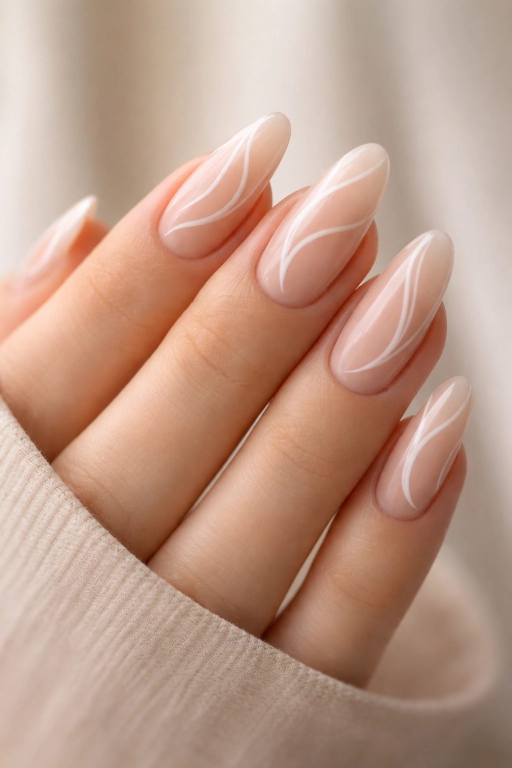 Nude almond nails with delicate white swirl designs