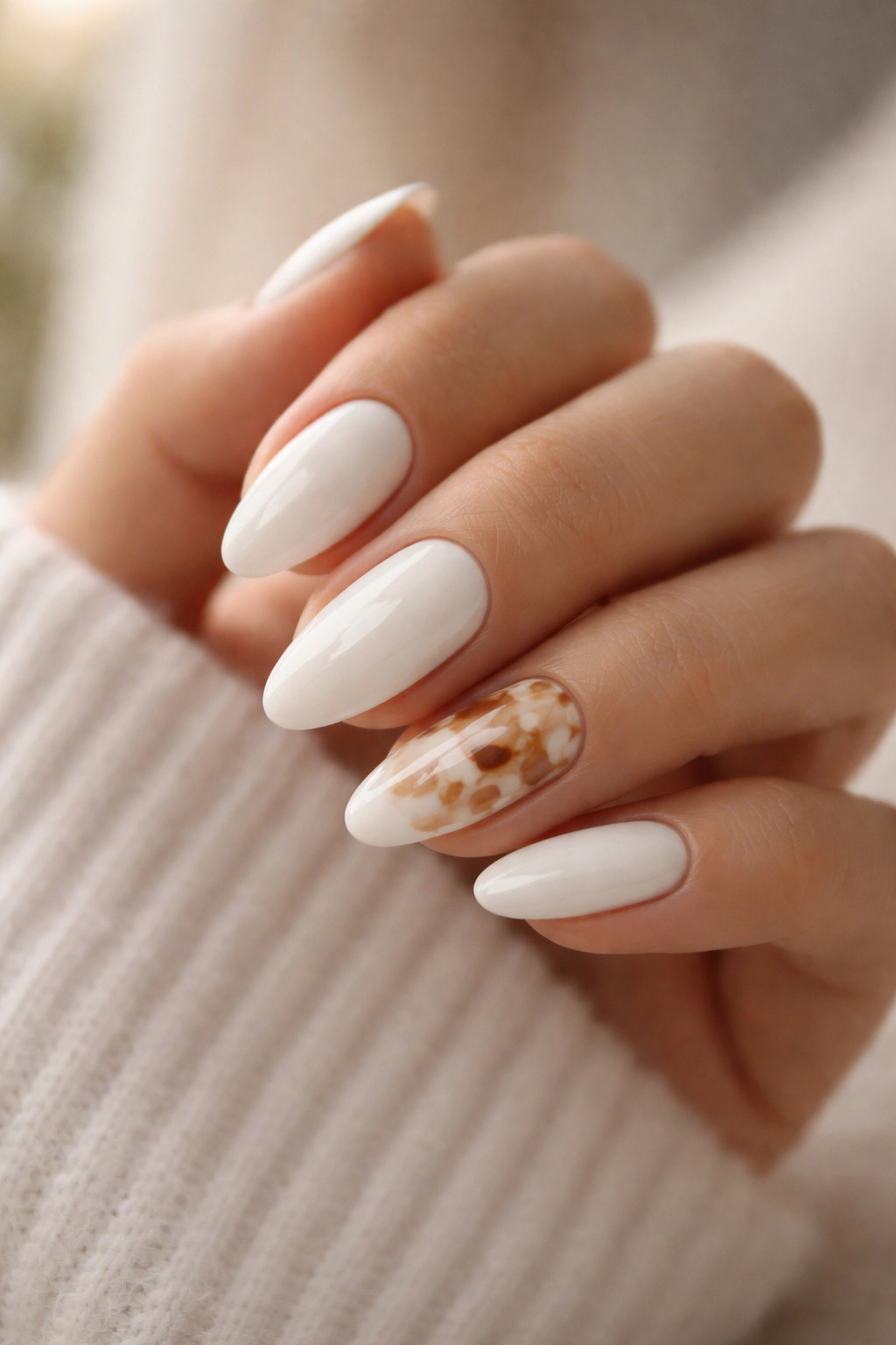 Close-up of a hand with white almond nails featuring white tortoiseshell accents on accent nails