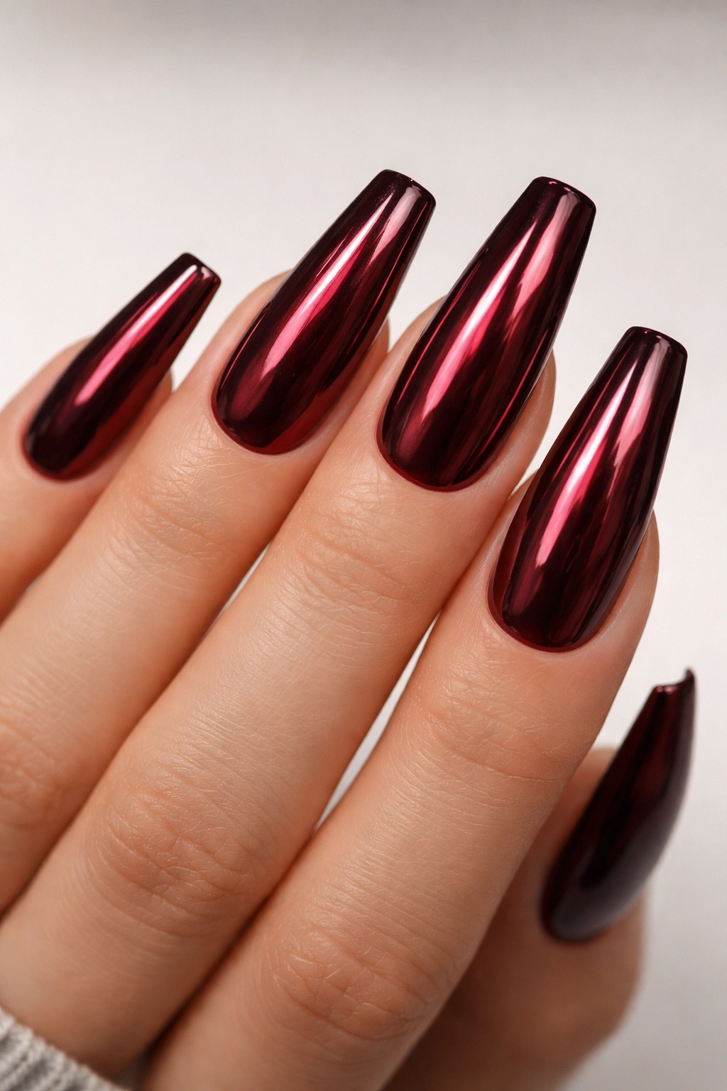 Close-up of wine red chrome coffin nails showing red base with reflective chrome