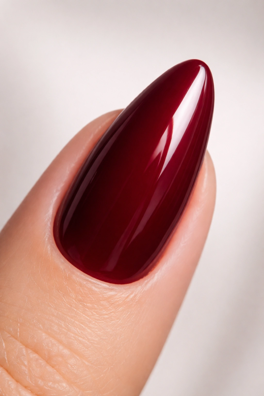 Close-up of an almond nail with a glossy wine red finish