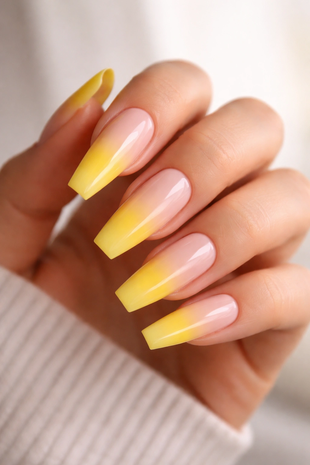 Close-up of yellow ombre coffin nails on a hand showing mid-nail fade and coffin shape