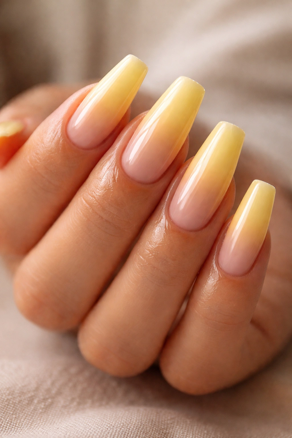 Close-up of well-maintained yellow ombre coffin nails with glossy finish and hydrated cuticles