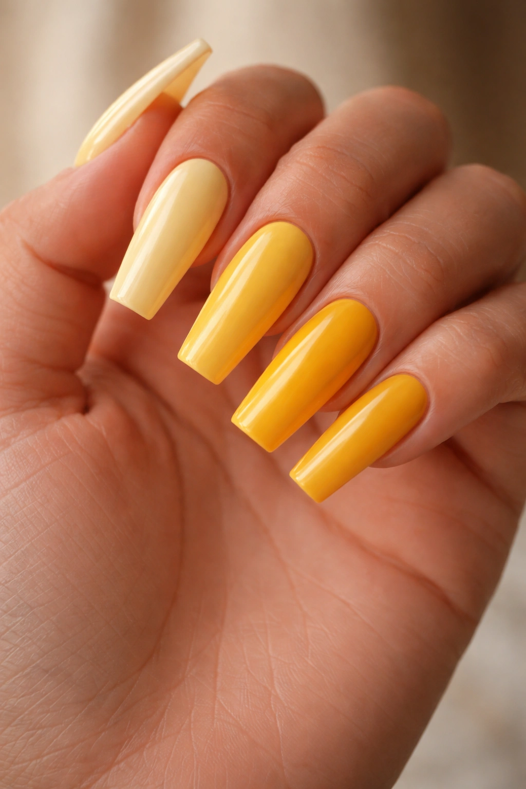 Hand with yellow coffin nails in multiple shades (butter, lemon, sunflower, mustard) for shade comparison