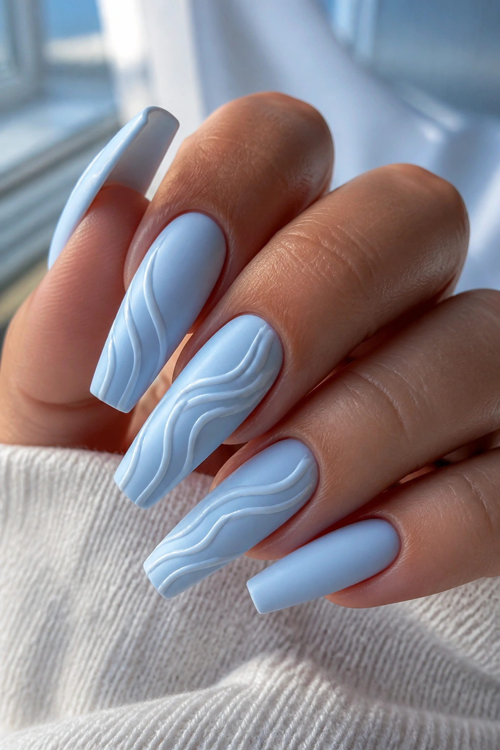 Close-up of baby blue coffin nails with 3D white wave lines