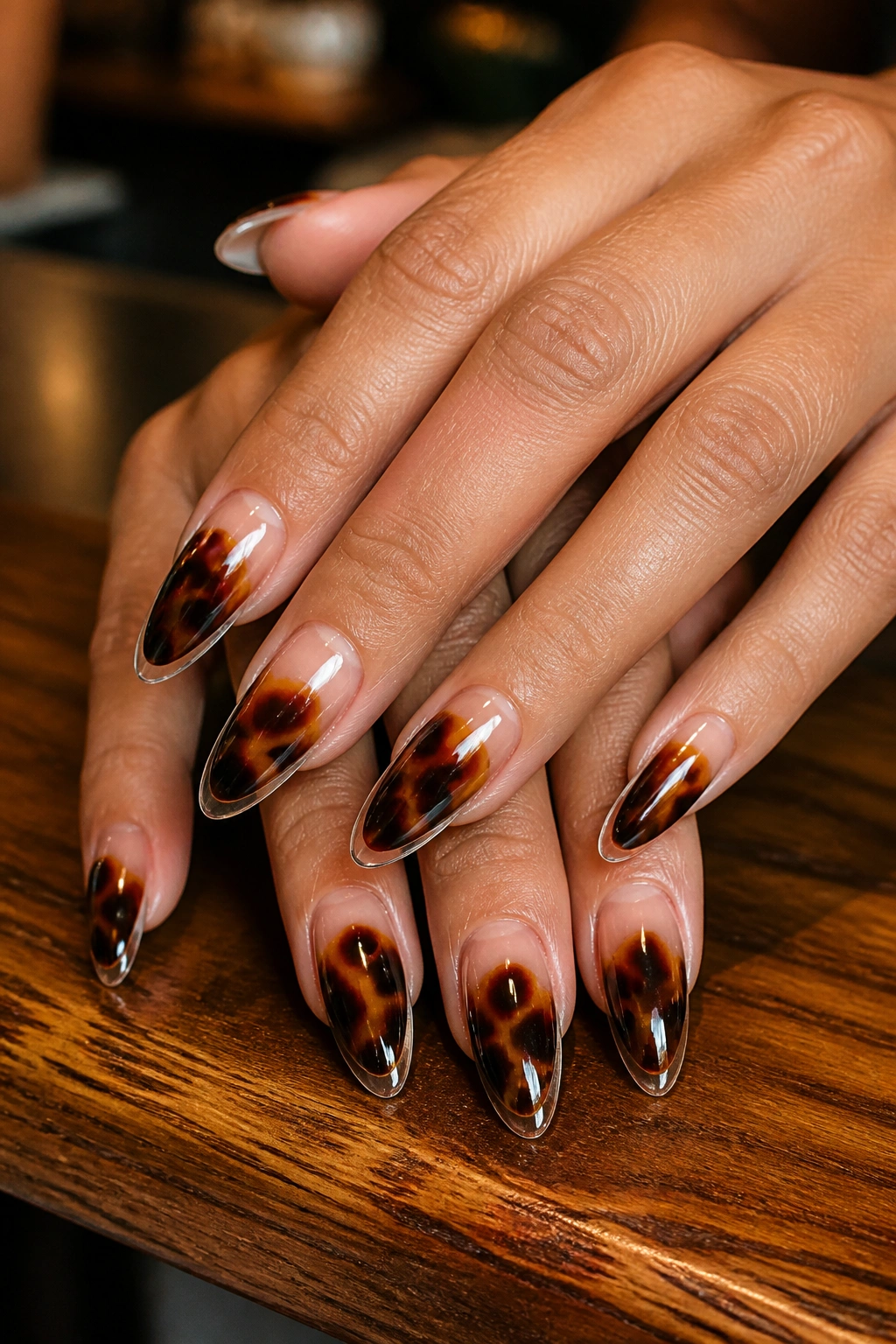 Close-up of tortoiseshell almond nails with clear edges on a real hand