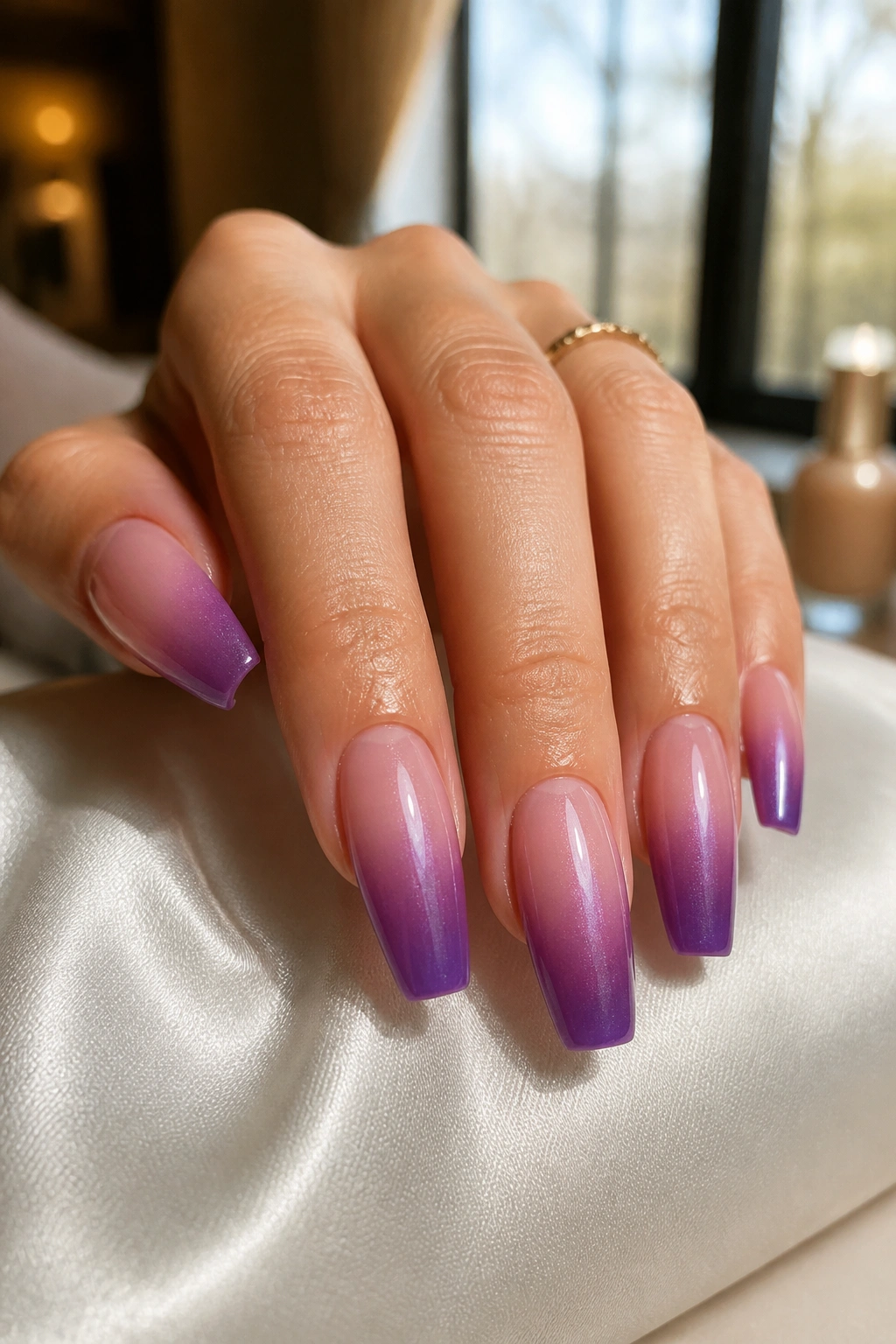 Close-up of nude-to-amethyst coffin nails in a smooth ombre on a real hand, medium length, in a salon setting