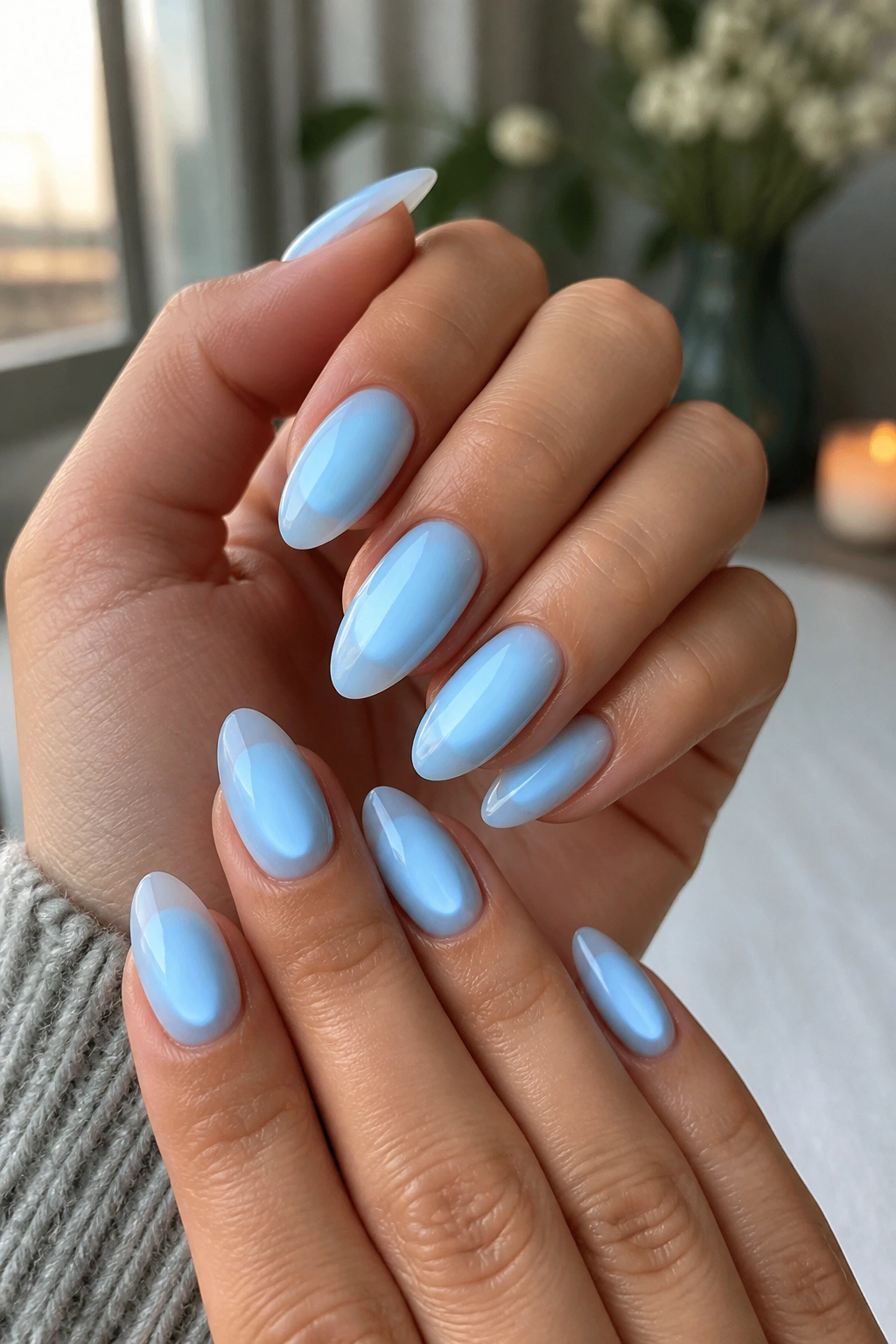Close-up of baby blue aura nails with soft halo glow on almond nails