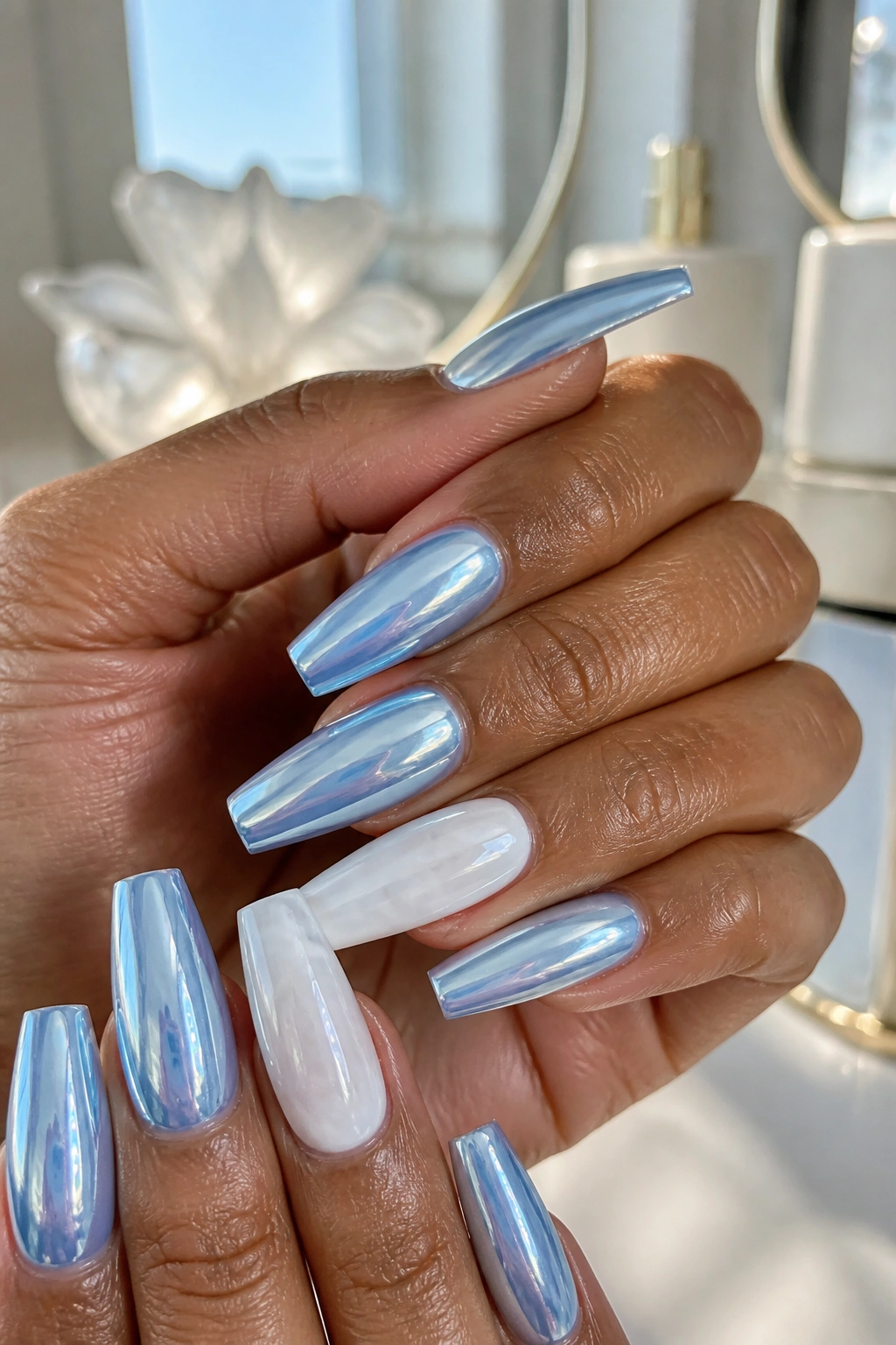 Close-up of baby blue chrome nails with cloud-white accent nails on a real hand.