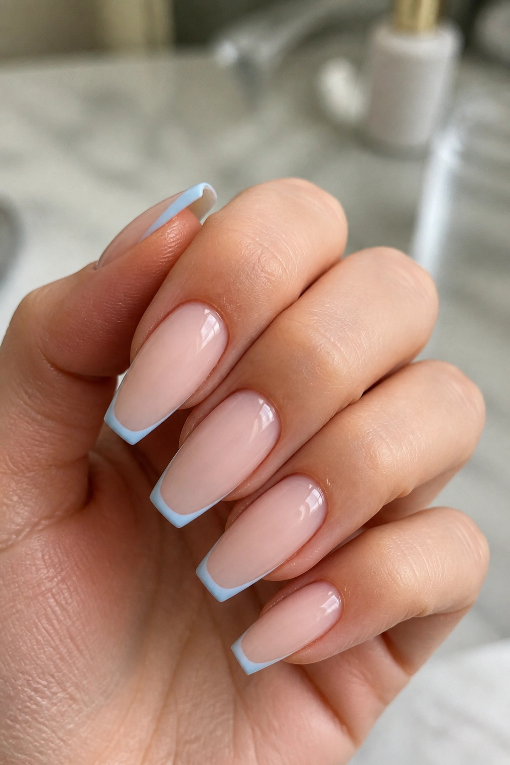 Real hand showing baby blue micro-French nails on nude base